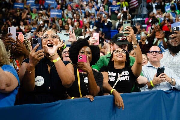 A close-up of supporters in the stands. Many are holding up their phones to capture the moment.