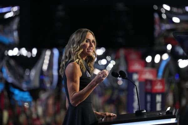 Lara Trump speaks into a microphone at a lectern, gesturing with one hand.