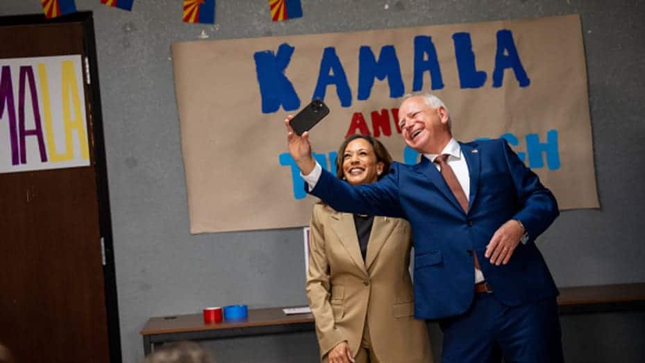 GLENDALE, ARIZONA - AUGUST 9: Democratic presidential candidate, U.S. Vice President Kamala Harris and Democratic vice presidential candidate Minnesota Gov. Tim Walz take a selfie in front of a sign that reads "Kamala and The Coach" during a stop at a campaign office on August 9, 2024 in Glendale, Arizona. Kamala Harris and her newly selected running mate Tim Walz are campaigning across the country this week. (Photo by Andrew Harnik/Getty Images)